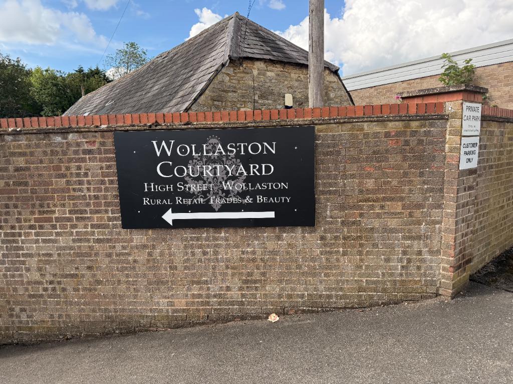 Wollaston Courtyard sign on the High Street wall